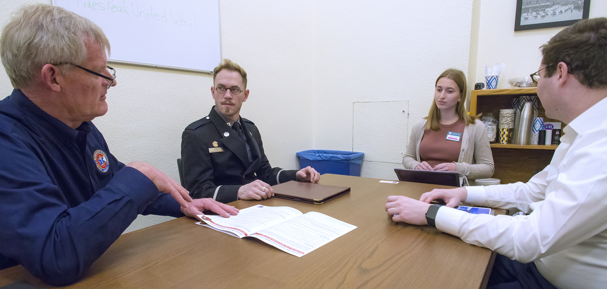 CEO Tim Dienst and Paramedic Zach Avery of Ute Pass Regional Health Services District and University of Denver EMS Director John Seward brief Taylor Furrh, aide to Speaker of the House Julie McCluskie about HB24-1218.